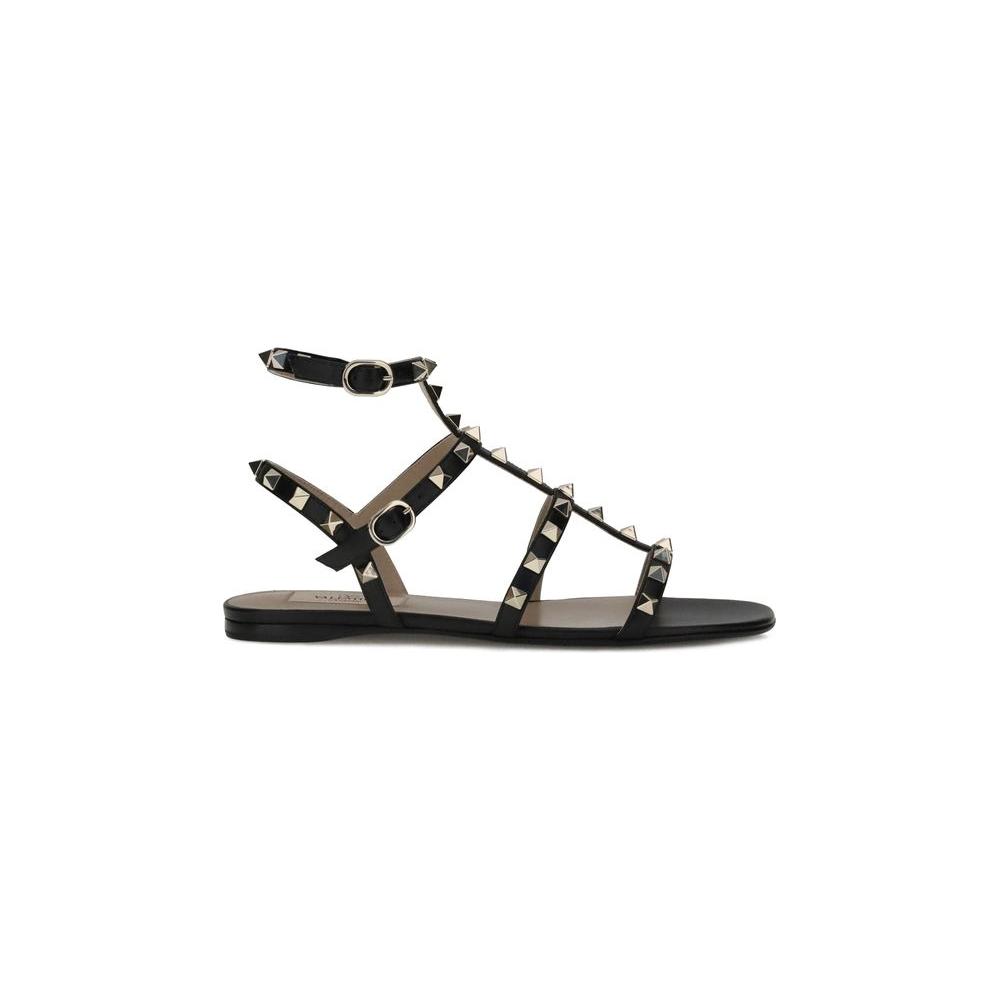 Valentino Garavani Rockstud SandalsValentino Garavani’s leather Rockstud Sandals combine bold style with refined comfort. Featuring a round toe and an adjustable ankle lap strap closure with a side buckle, they offer a secure and personalized fit. The fla