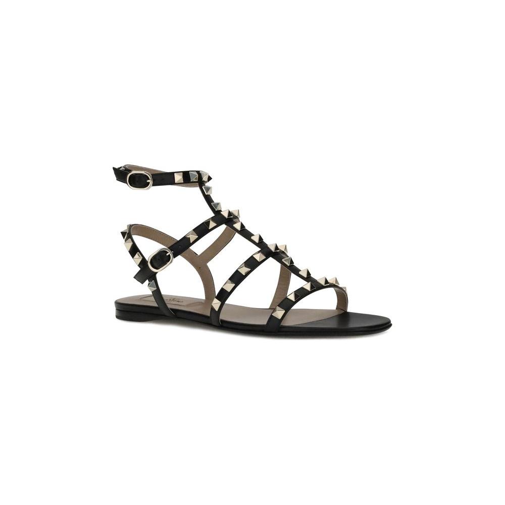 Valentino Garavani Rockstud SandalsValentino Garavani’s leather Rockstud Sandals combine bold style with refined comfort. Featuring a round toe and an adjustable ankle lap strap closure with a side buckle, they offer a secure and personalized fit. The fla