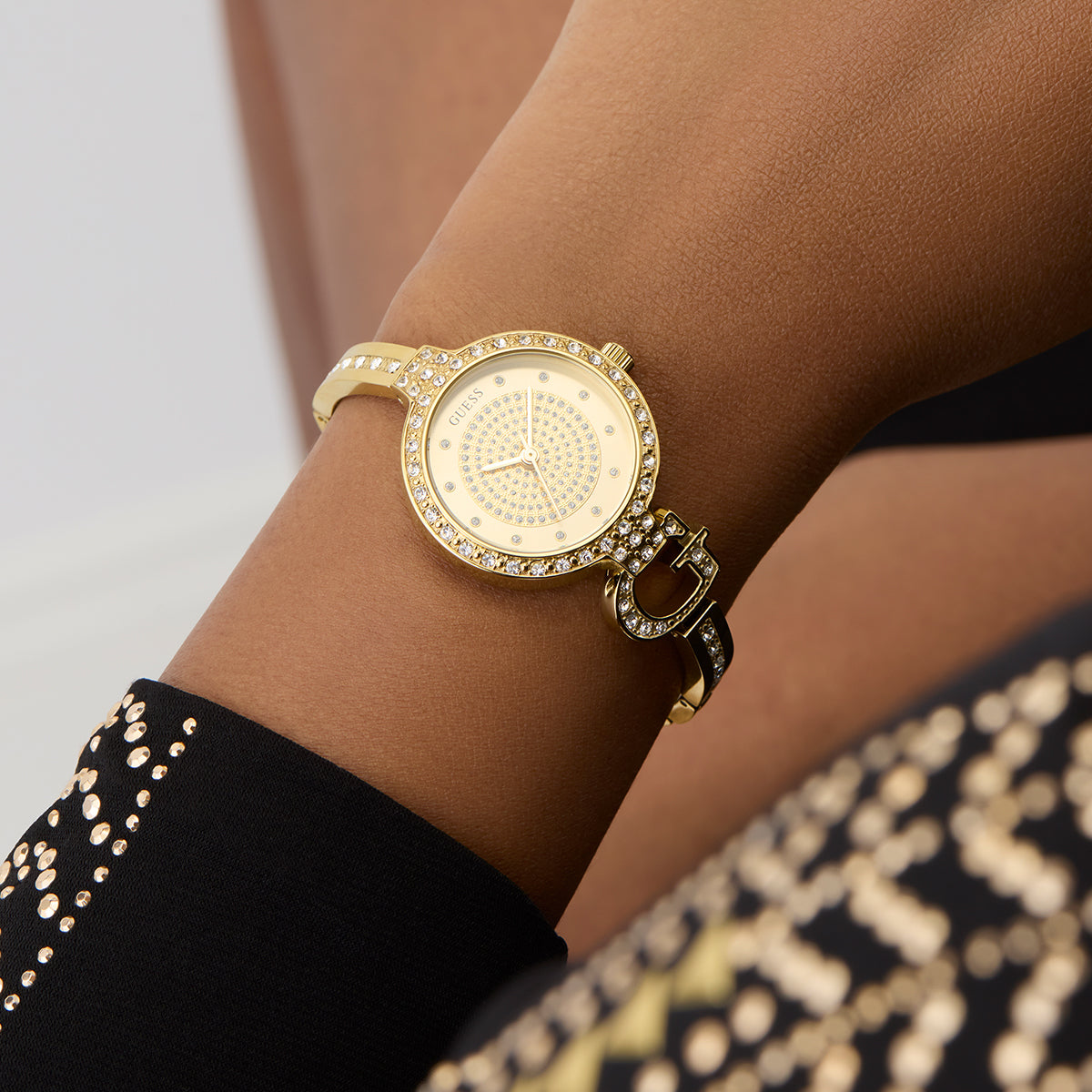 Alt Tag: Elegant wrist showing GUESS Mod. GISELLE watch with a gold band and diamond accents, combining luxury and style.