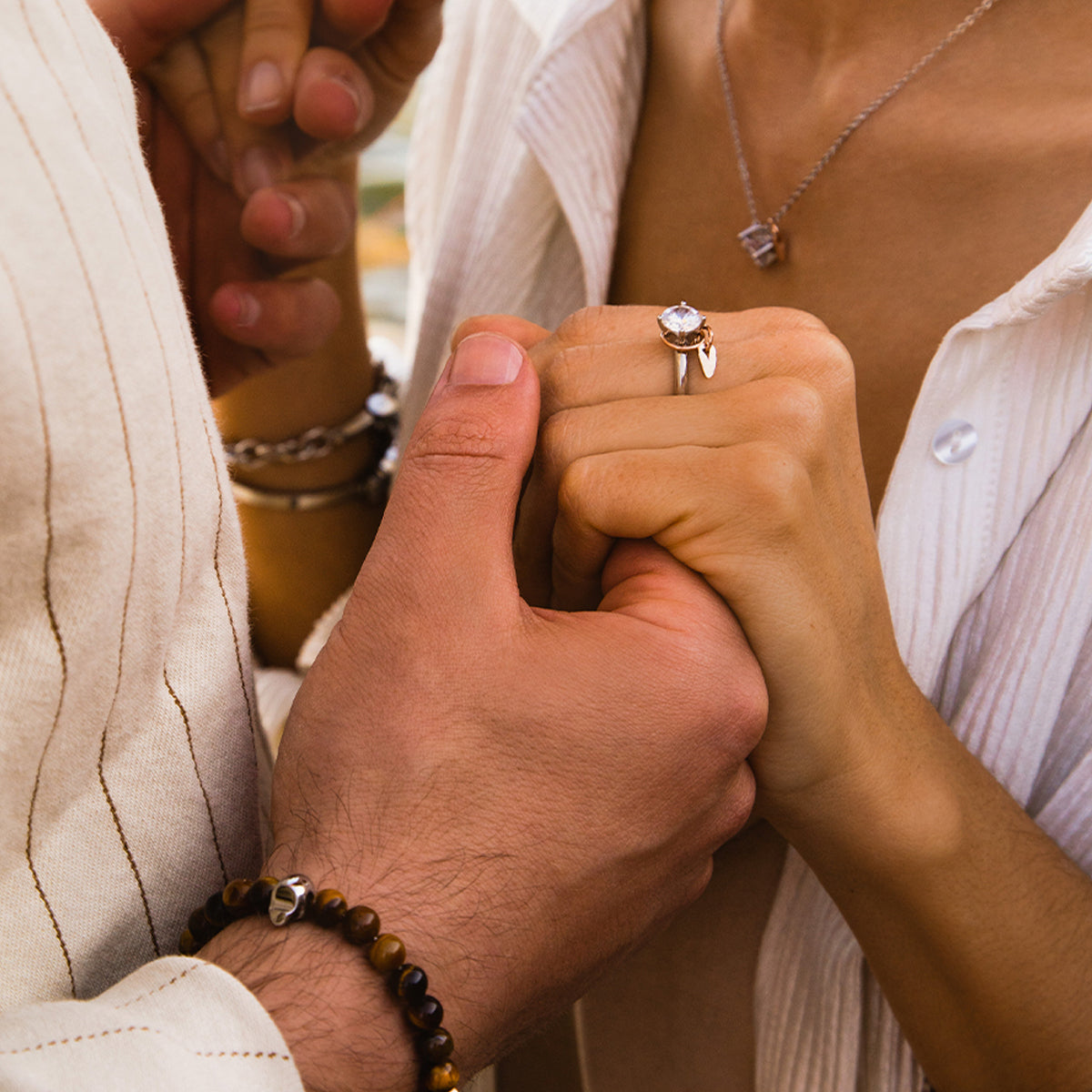 Couple holding hands, focusing on engagement ring with AN JEWELS JEWELRY Mod. AL.RLFY01-8, highlighting elegance and connection.