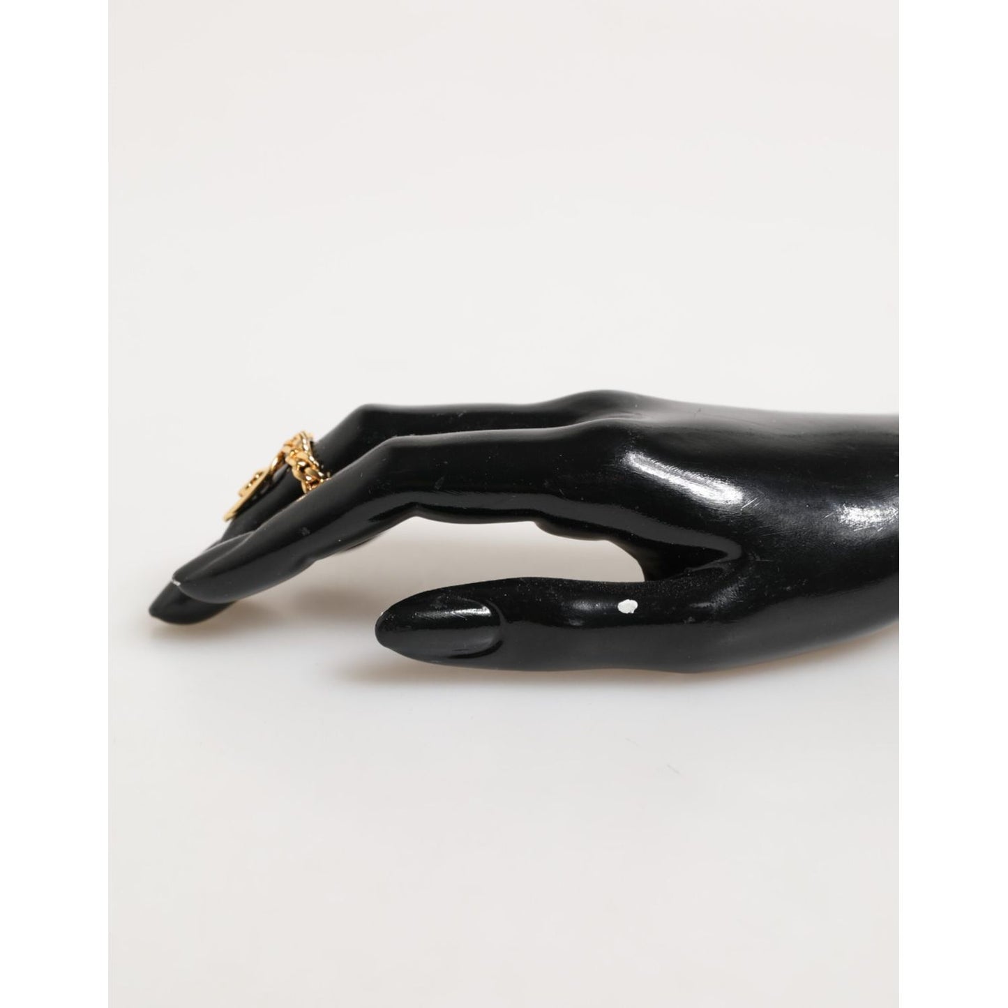 Elegantly displayed Dolce & Gabbana Gold Tone Brass Oval DG Logo Chain Adjustable Ring on black mannequin hand.