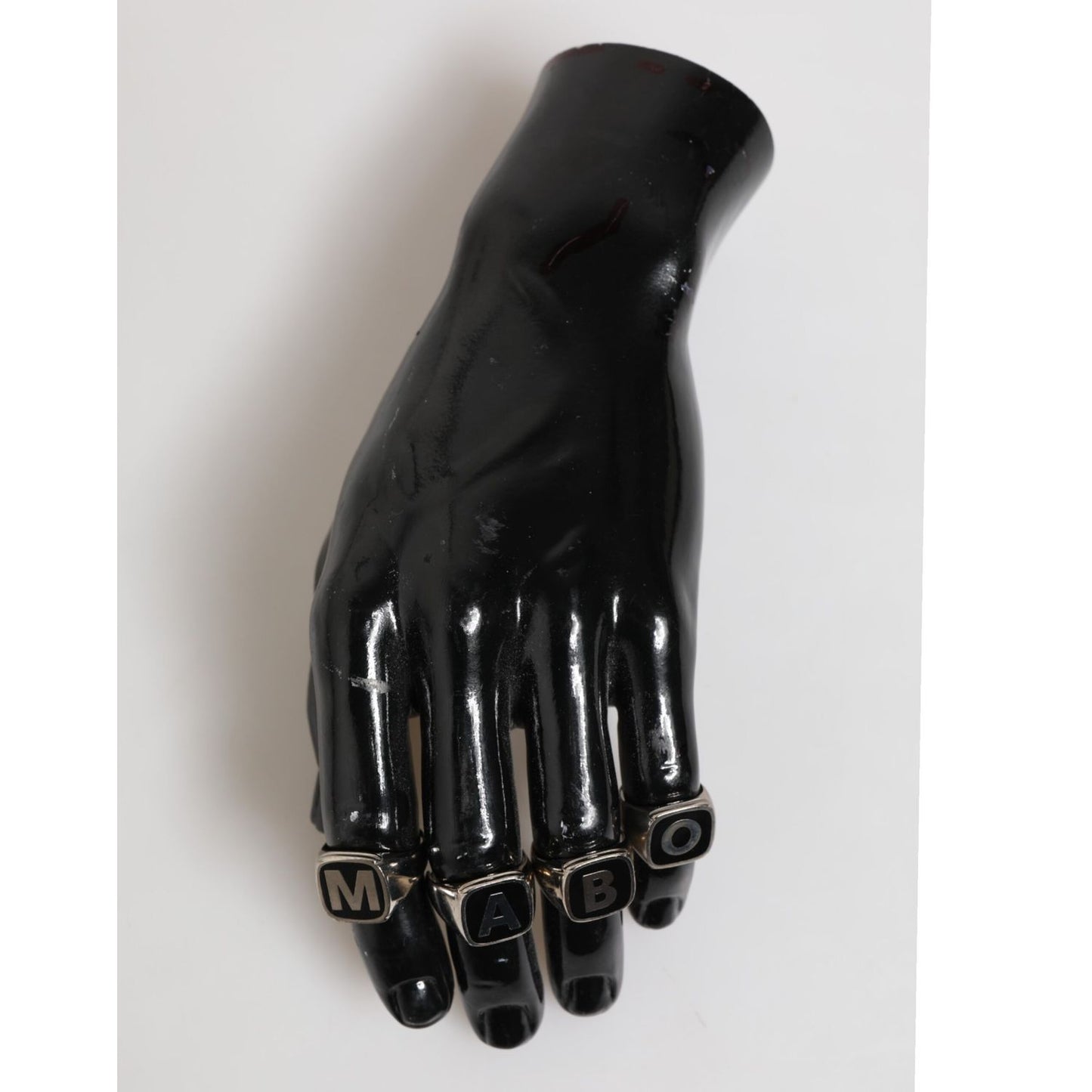 Black hand display featuring Dolce & Gabbana Silver Tone Brass Lettering Set 5 Pieces Adjustable Ring with 'M A B O' letters.