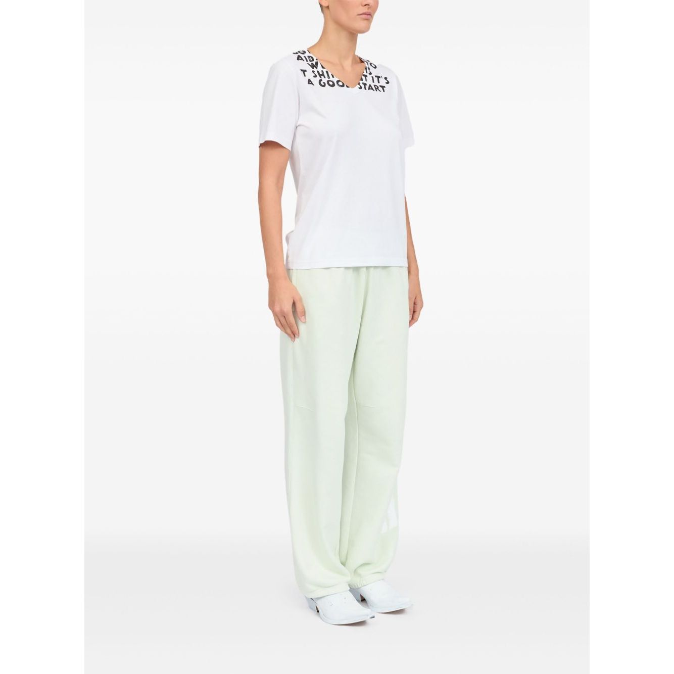 Model wearing MM6 Maison Margiela T-shirts and Polos White V-neck graphic print, short sleeves, side view.