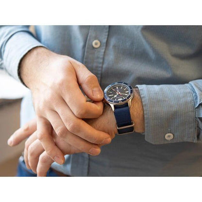 Man wearing NAUTICA Mod. NAPABS904 watch with blue strap, quartz analog movement, 43mm case, 5 ATM water resistance, in official packaging.
